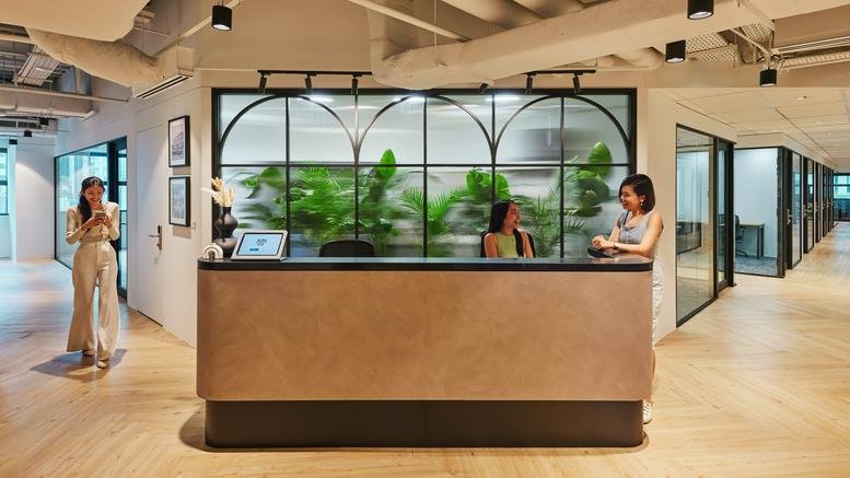 Professional reception area with a wood-paneled desk and green plant feature wall at Hong Leong Building.