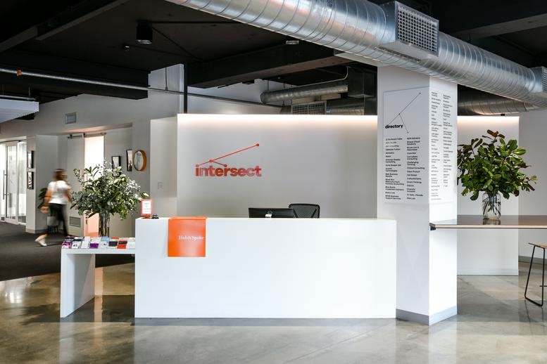 Bright, modern reception area at 167 Flinders Street, Adelaide City featuring a white desk and greenery.