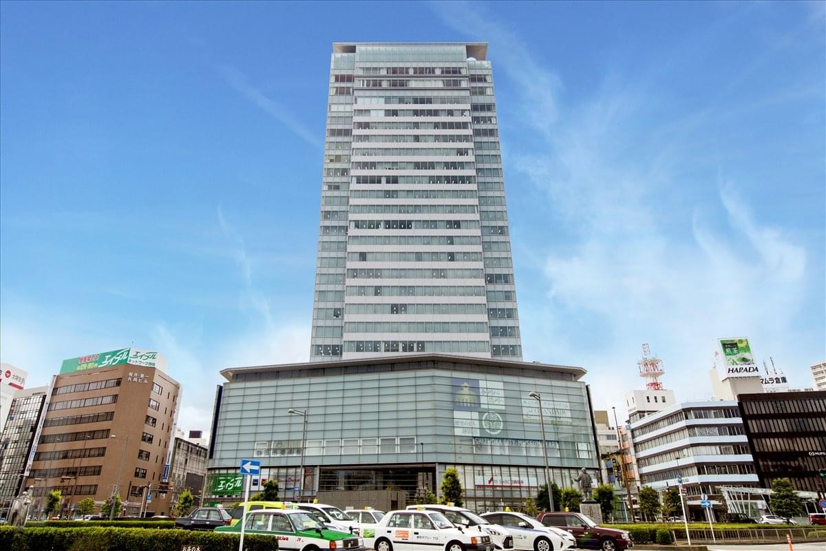 Exterior view of the soaring glass and concrete Aoi Tower under a clear blue sky.