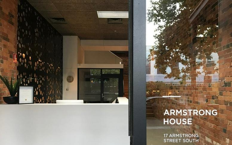 Reception area at Armstrong House with white desk, brick walls, and decorative screen.