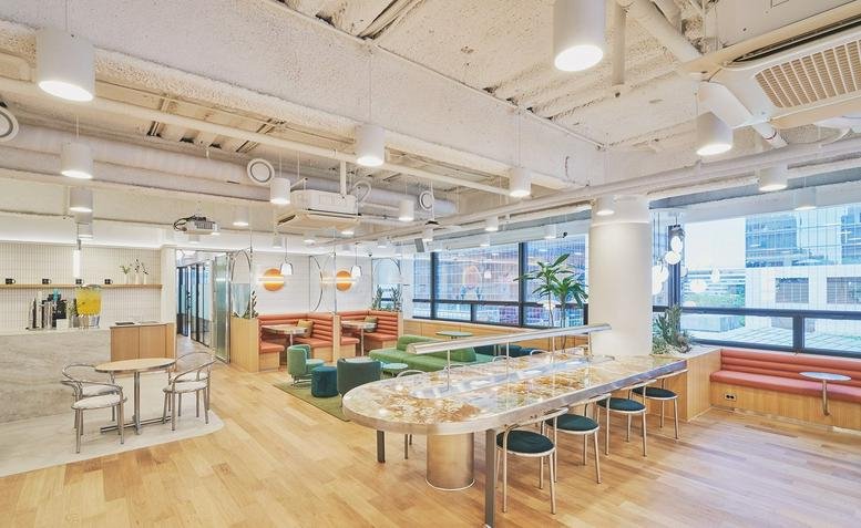 Spacious sunlit lounge at 17, Gukjegeumyung-ro 2-gil featuring a long communal table and colorful seating.