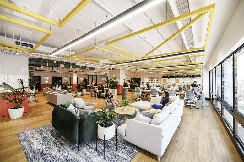 Spacious communal lounge at Office Space to Rent on Pitt Street, Sydney Central Business District with yellow ceiling.