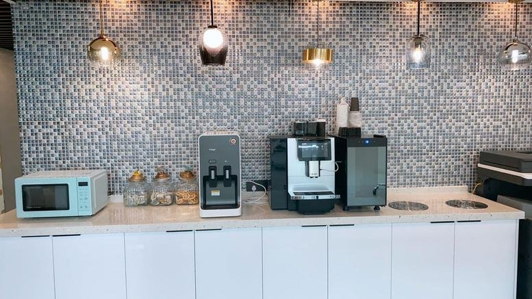 Pantry area at Jing An New Century Building with coffee machines, microwave, and patterned grey backsplash.