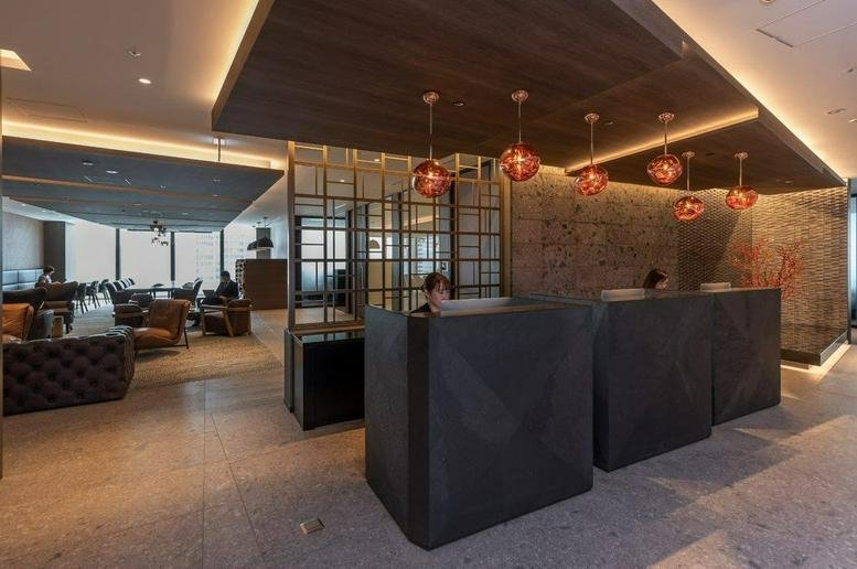 Spacious reception area with dark wood ceilings and copper pendant lights at The World Trade Center Building, Tokyo.