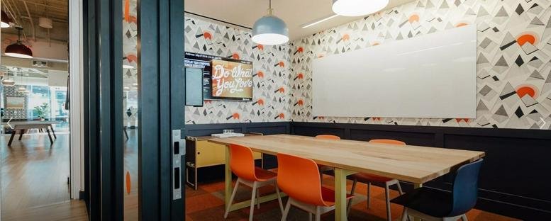 Colorful meeting room at 18 Nahalat Itzhak St with patterned wallpaper and orange chairs.