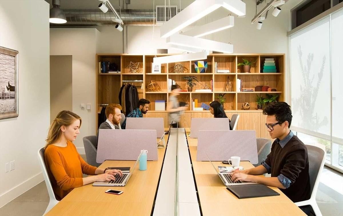 Bright open-plan workspace at 18 Robinson Road with modern pendant lighting and wooden desks.