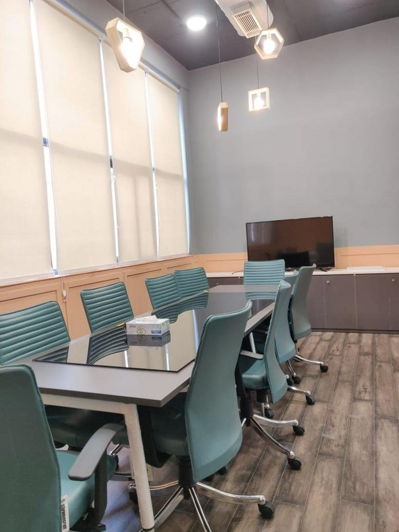 Spacious boardroom at 18B, Sector-32, Gurgaon featuring a glass-top table and geometric pendant lights.
