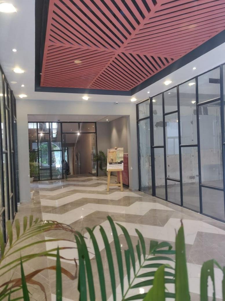 Spacious reception lobby at 18B, Sector-32, Gurgaon featuring a geometric patterned floor and slatted ceiling.