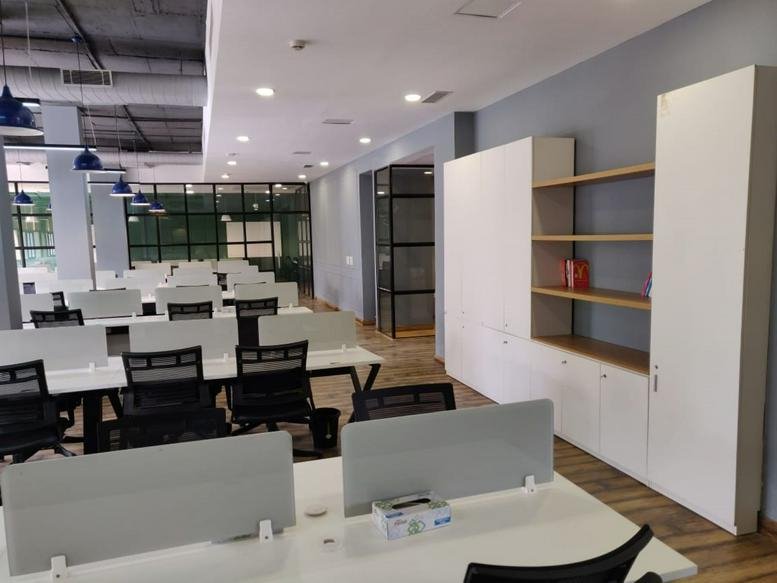 Open-plan office space at 18B, Sector-32, Gurgaon featuring white desks and a tall storage unit.