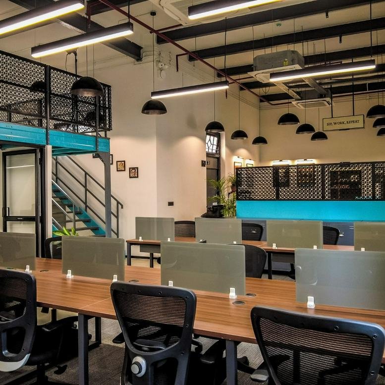 Spacious industrial-style coworking area at 19, RN Mukherjee Road with mezzanine and wooden desks.