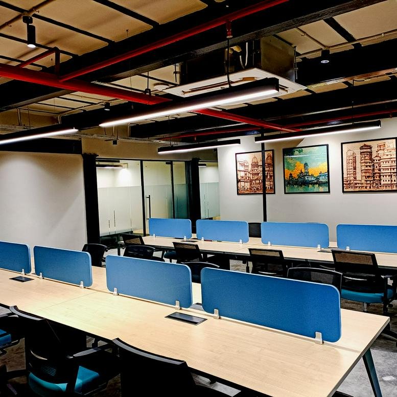 Spacious open-plan workspace at 19, RN Mukherjee Road with long wooden desks and blue privacy screens.