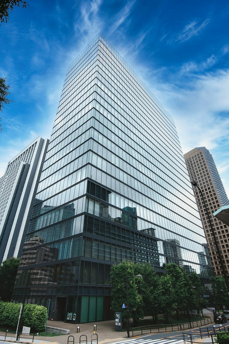 Exterior view of the glass-facade Toranomon Towers office building under a blue sky.