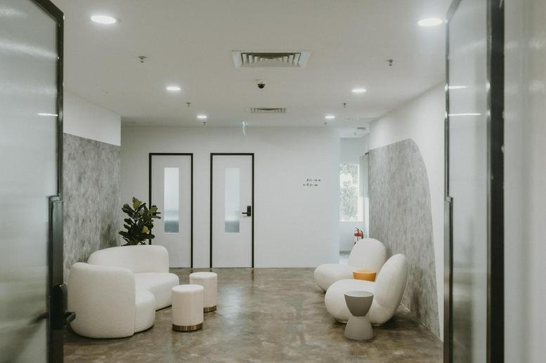 Spacious reception lounge at Menara Manulife with white curved sofas and textured grey feature walls.