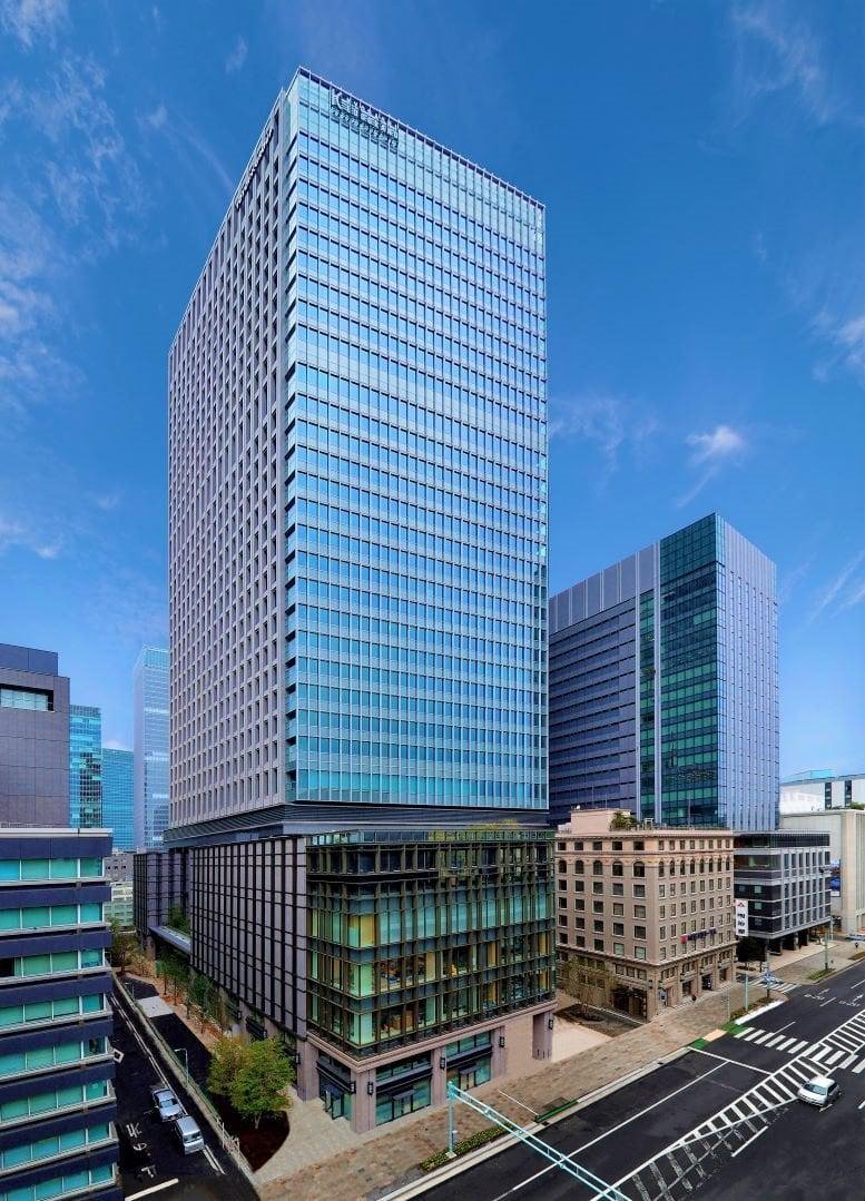 Exterior view of the glass-facade Kyobashi Edogrand building against a blue sky.
