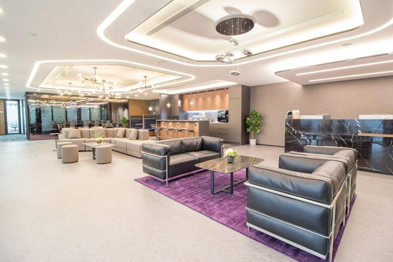 Spacious reception lounge with sleek leather sofas, a purple rug, and recessed ceiling lighting.