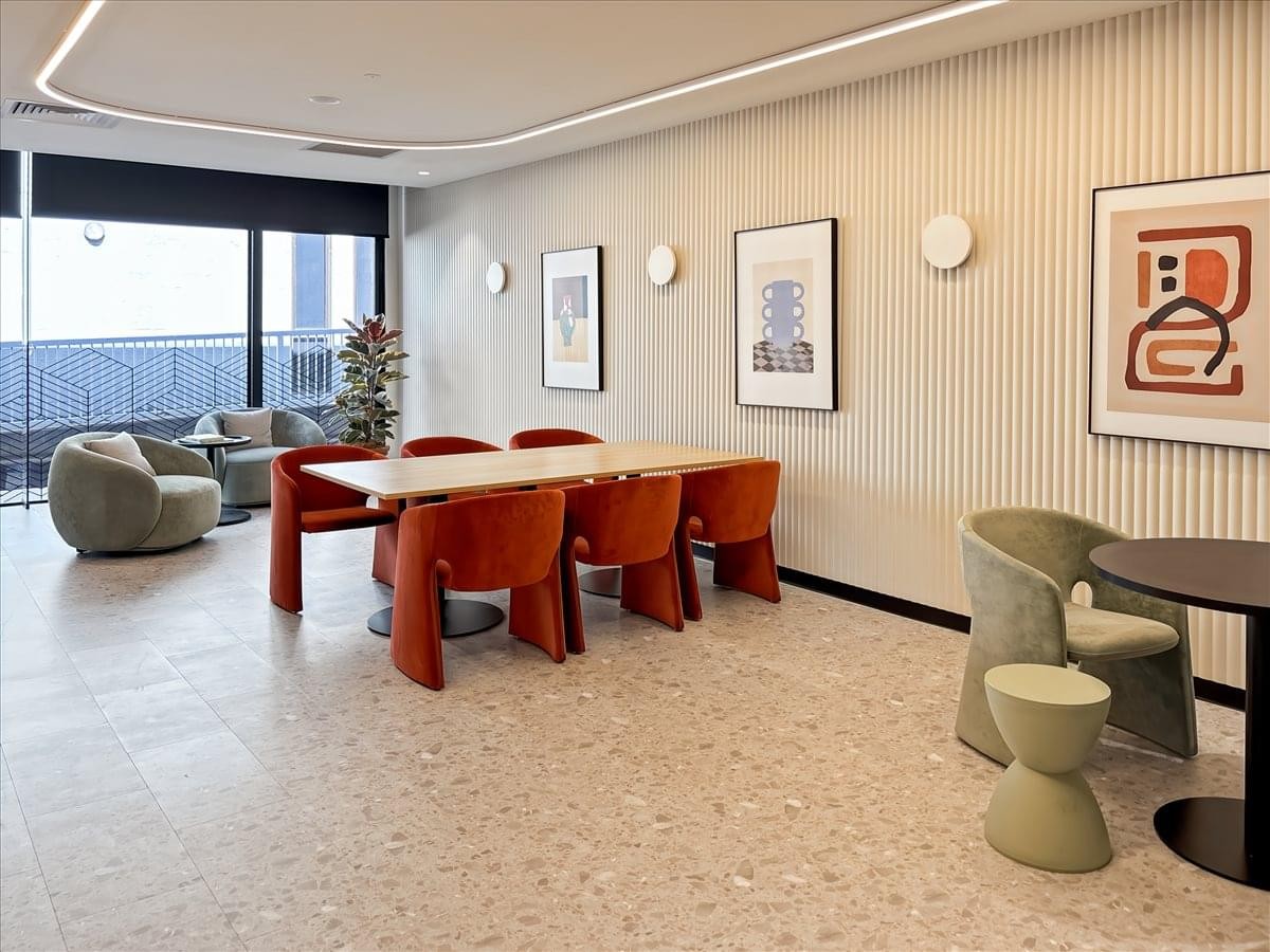 Modern communal breakout space at 2-3 Greenhill Road, Wayville, featuring orange chairs and soft lighting.