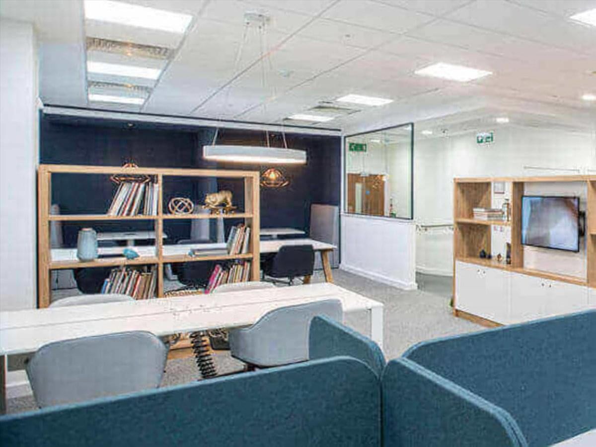 Bright coworking area at 2-4-6 Kanaikecho, Oita, Japan with bookshelves and comfortable seating.