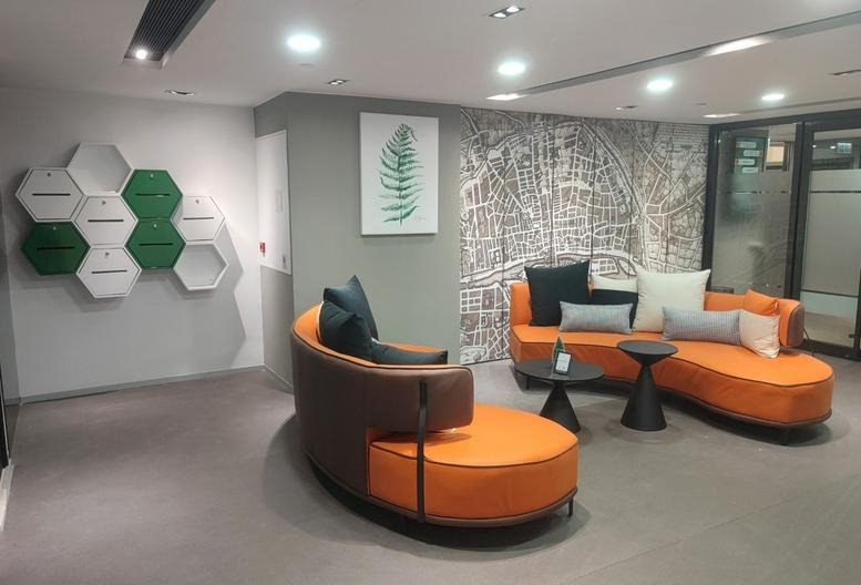 Lounge area at Hong Kong Spinners Industrial Building Phase 5 with orange curved sofas and graphic wall art.
