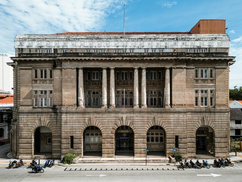 Grand historic stone facade of the 2, Lebuh Pantai building featuring arched entrances and classical columns.