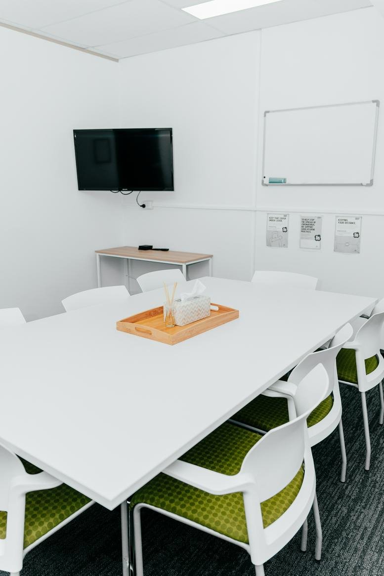Professional meeting room at 2 Portside Crescent, Newcastle featuring a large white table and green cushioned chairs.