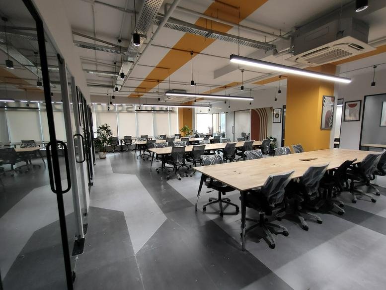 Spacious open-plan coworking area with wooden tables and yellow feature pillars.