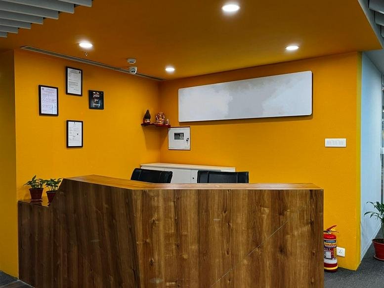 Modern wooden reception desk against a vibrant yellow wall at 2nd Floor, Ackruti Star.