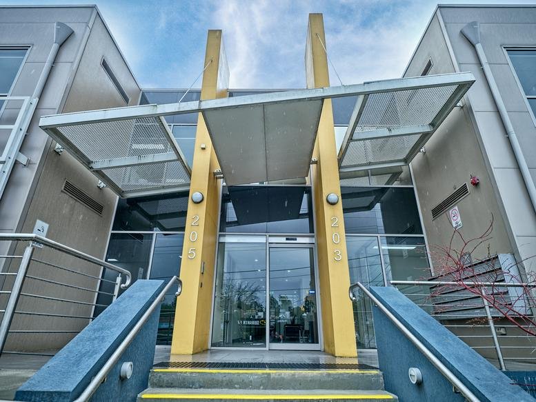 Exterior view of the modern glass and yellow facade entrance at 203 Blackburn Road.