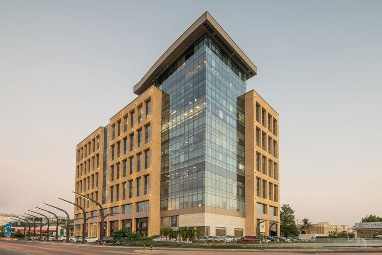 Exterior view of the contemporary glass and stone Jameel Square Building under a clear sky.