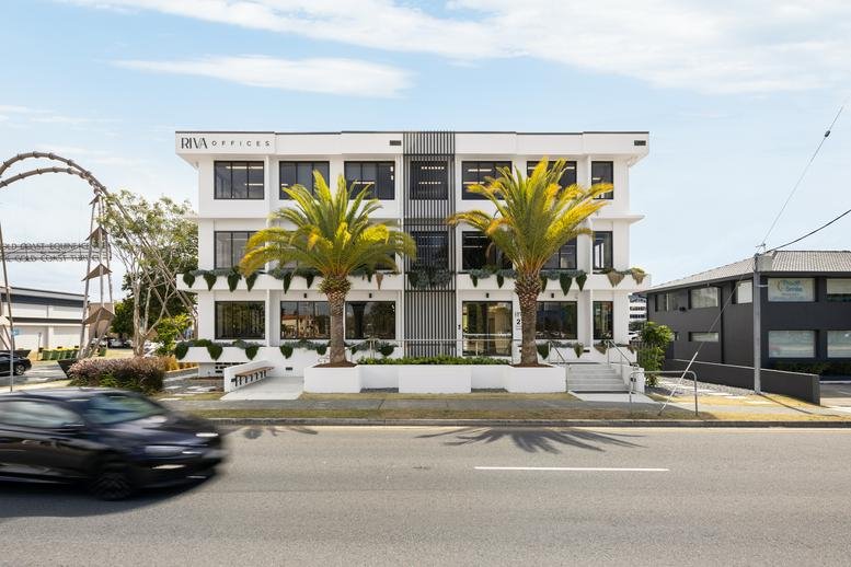 Exterior view of the white three-story office building at 21 Crombie Avenue with palm trees.