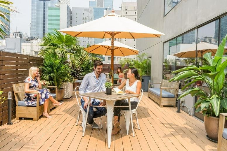 Rooftop terrace at 21/F The Phoenix Building, 23 Luard Road with wooden decking, umbrellas, and potted plants.