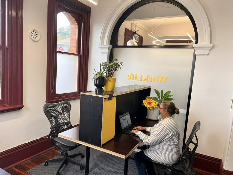 Workspace with a yellow-accented desk and ergonomic chair by a large arched window.