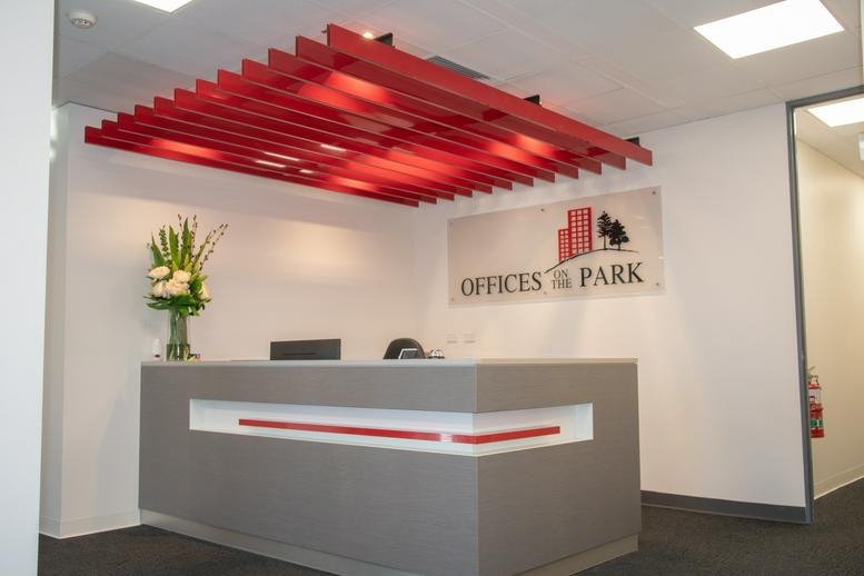 Reception area at 22 Greenhill Road, Wayville with a modern grey desk and a striking red slatted ceiling feature.