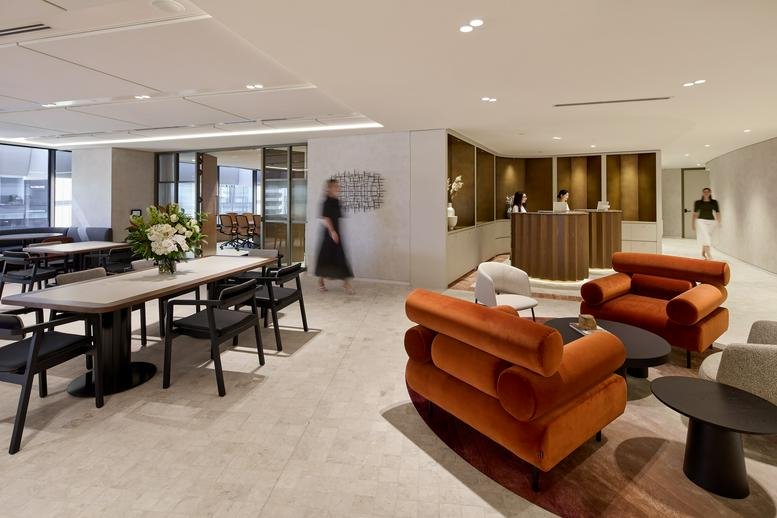 Contemporary lounge area with plush orange armchairs and a long communal table.