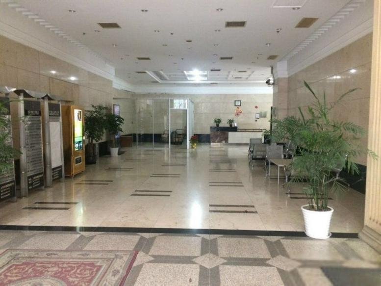 Large building lobby with marble floors and potted plants.