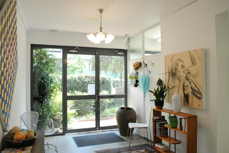 Sunlit entrance at 23 Atchison Street, St. Leonards, Sydney with glass doors and artistic decor.