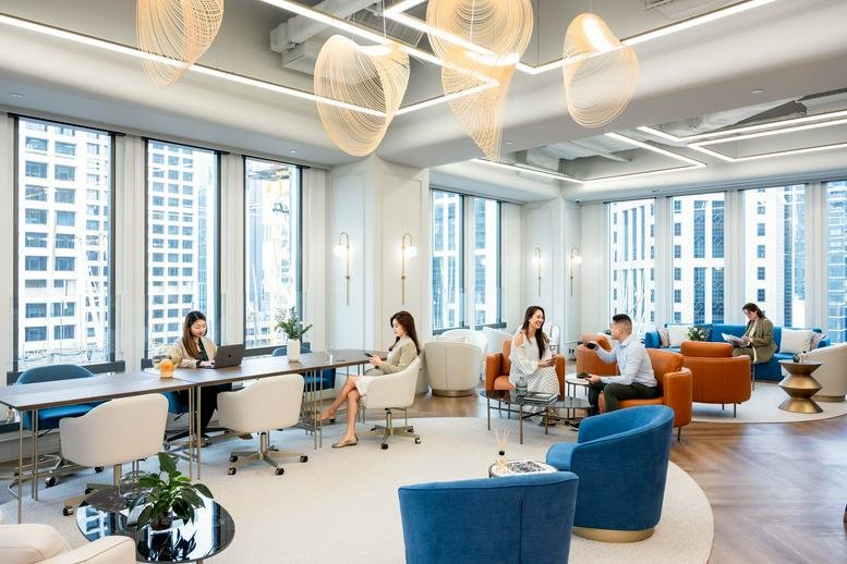 Spacious communal lounge at One Chinachem Central with designer lighting, blue armchairs, and floor-to-ceiling windows.