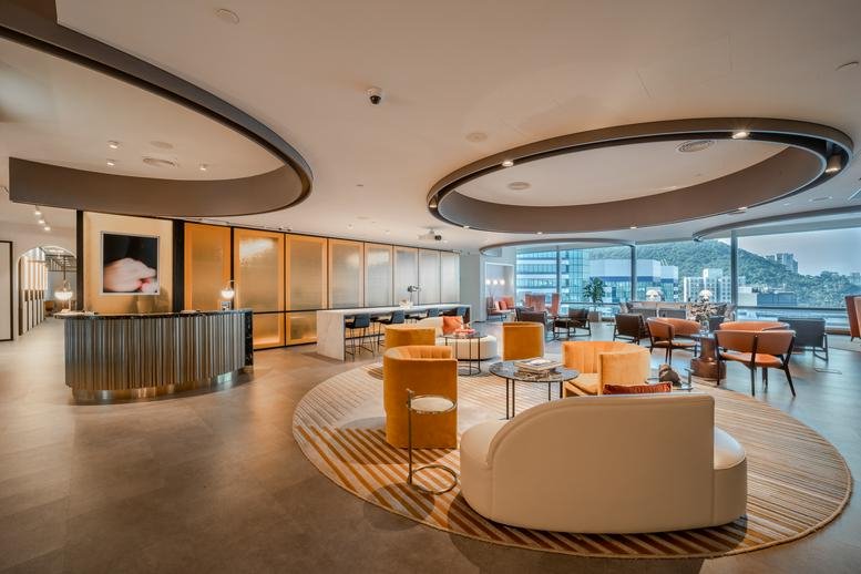 Reception and lounge at One Taikoo Place with circular ceiling lights and warm yellow armchairs.