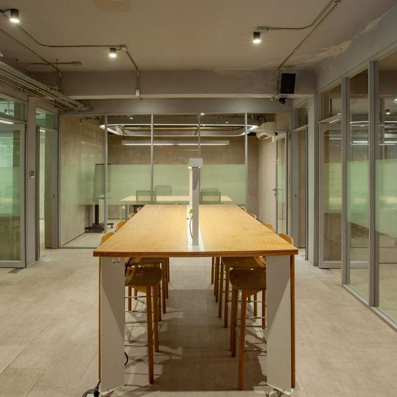 Spacious coworking area with a long wooden communal table at 235/3-5, Sukhumvit Road, Klongtoey Nue, Bangkok.