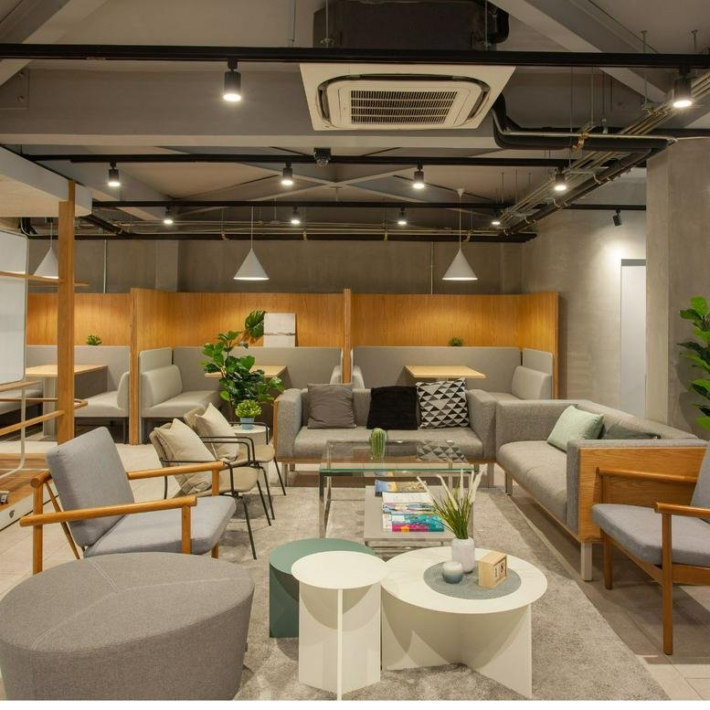 Modern lounge area with grey sofas, armchairs, and circular coffee tables under industrial track lighting.