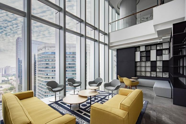 High-ceiling lounge at Guangzhou International Commercial Center with yellow sofas and floor-to-ceiling city views.
