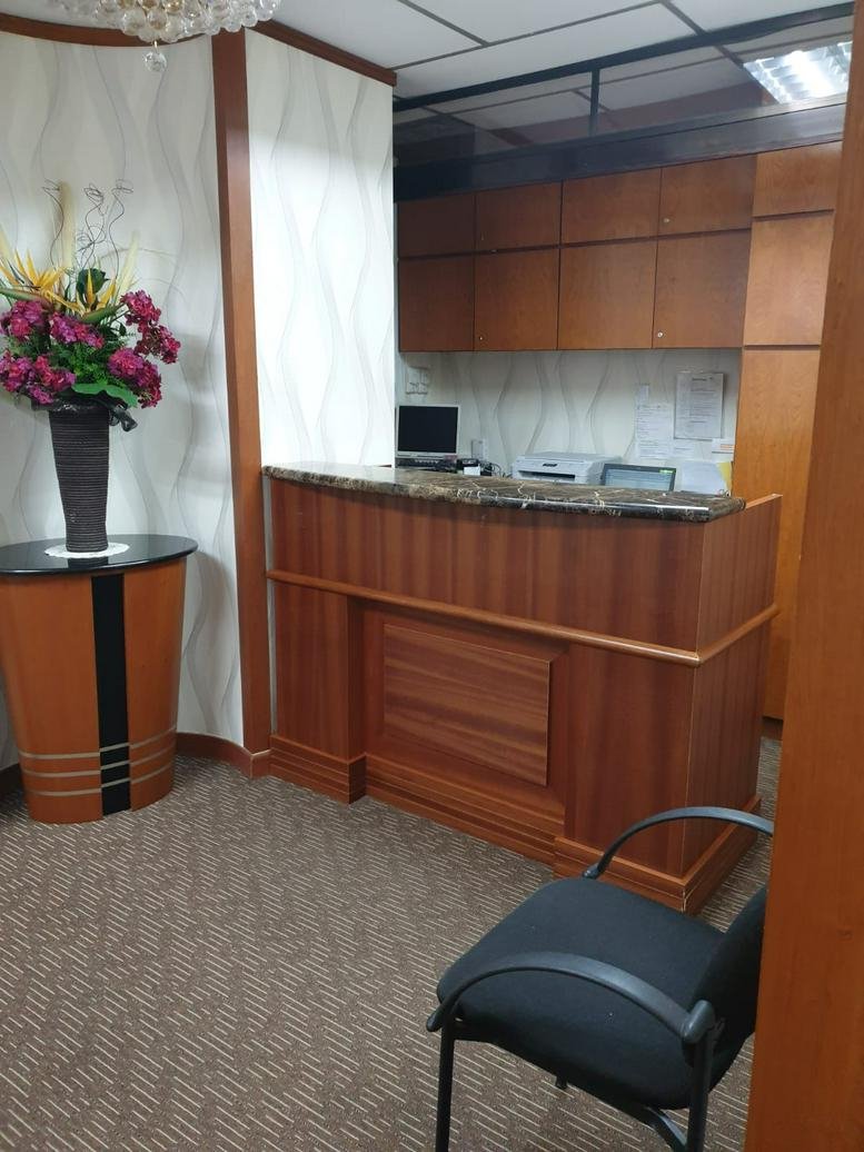 Wooden reception desk at International Plaza with marble countertop and floral arrangement.