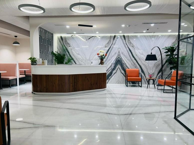 Reception area at 24 Vittal Mallya Road, UB City, Level 10, Concorde Block featuring marble walls and orange armchairs.