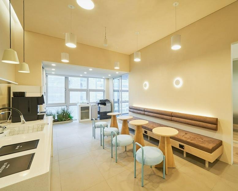 Breakout area at 242, Teheran-ro, Seoulleung 2 featuring light wood tables and soft blue chairs.