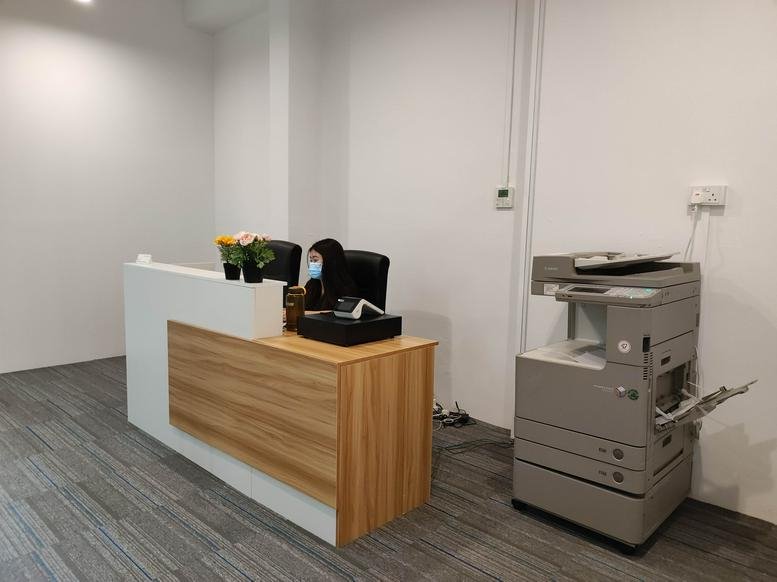 Modern reception area with a minimalist white and wood-paneled desk and large copier.