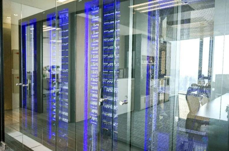 Entrance to the Guangzhou South Media Centre featuring sleek glass walls with vibrant blue vertical lighting.