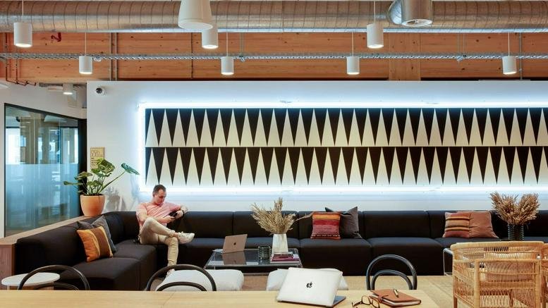 Spacious communal lounge at 25 King Street Bowen Hills with a long black sofa and geometric wall art.