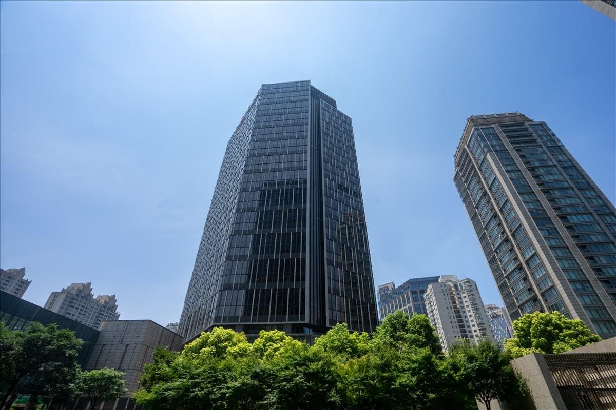 Exterior view of the glass-facade Infinitus Tower under a bright blue sky.