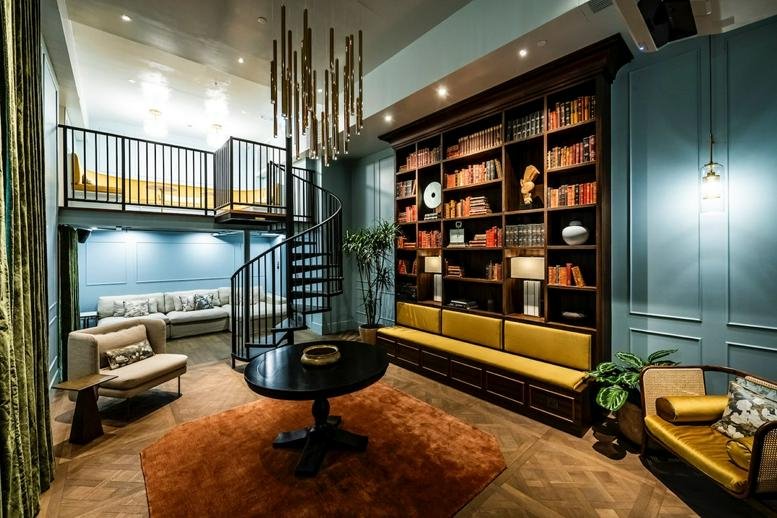 Spacious communal lounge at Eastern Harbour Centre with a library wall and spiral staircase.