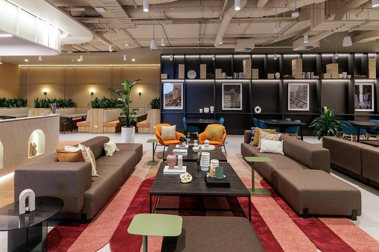 Spacious communal lounge at 287 Lonsdale Street with brown sofas, orange armchairs and a red striped rug.