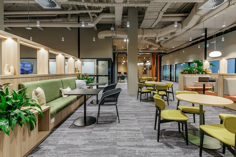 Casual breakout area with lime green chairs and booth seating along a wooden wall.